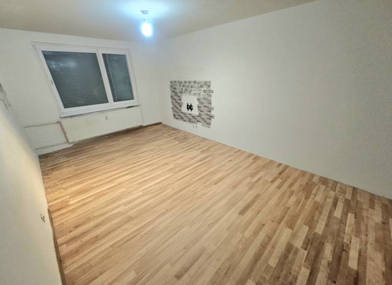 Wohnzimmer mit Holzboden und Fenster in einer 3-Zimmer-Wohnung.