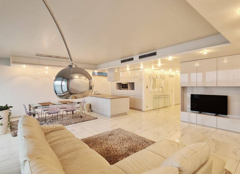 Innenraum einer 3-Zimmer-Wohnung mit offener Küche und weißem Sofa.