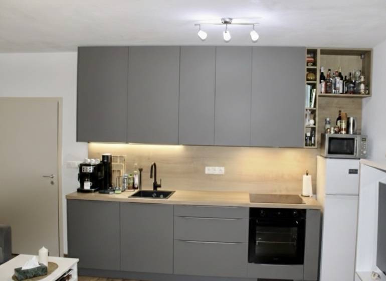 Küche in einer 2-Zimmer-Wohnung mit dunkelgrauer Küchenzeile und Geräten.