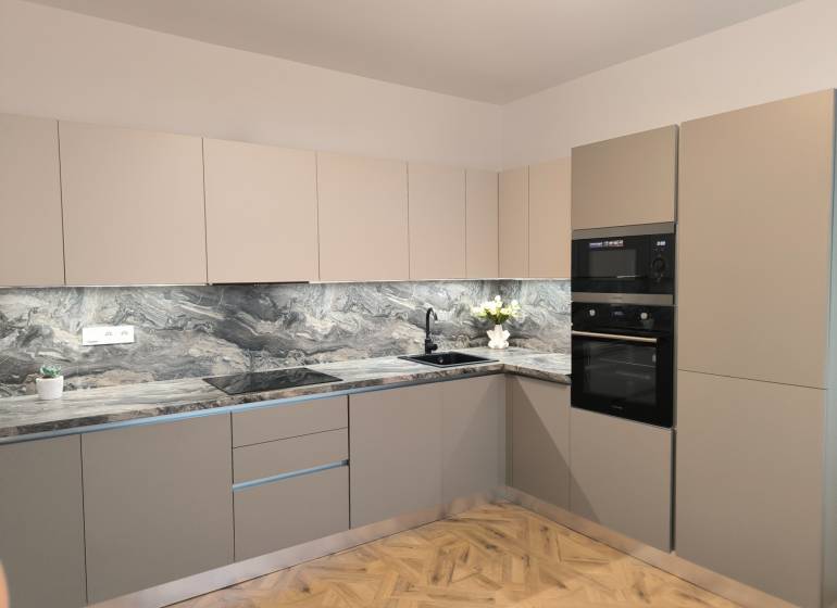 Küche in einer 4-Zimmer-Wohnung mit einer Marmor-Arbeitsplatte und einem Boden in Holzoptik.