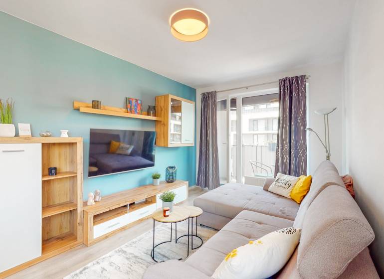 Wohnzimmer in einer 3-Zimmer-Wohnung mit einem bequemen Sofa und einem Balkon, Boden mit Holzdekor.