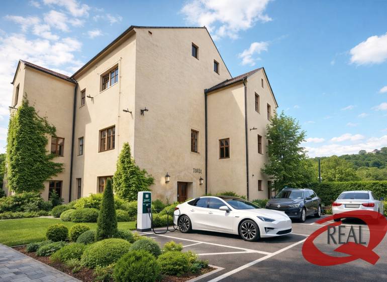 Ein Gebäude in Veľké Uherce mit Grünflächen und einer Ladestation für Elektroautos auf dem Parkplatz.