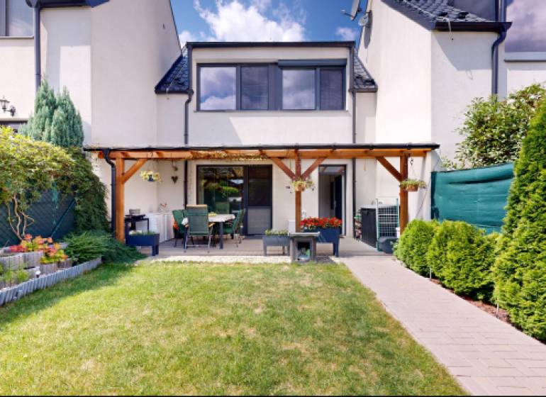 Garten und Terrasse bei einem Einfamilienhaus in Stupava mit gepflegtem Rasen und Blumenbeet.