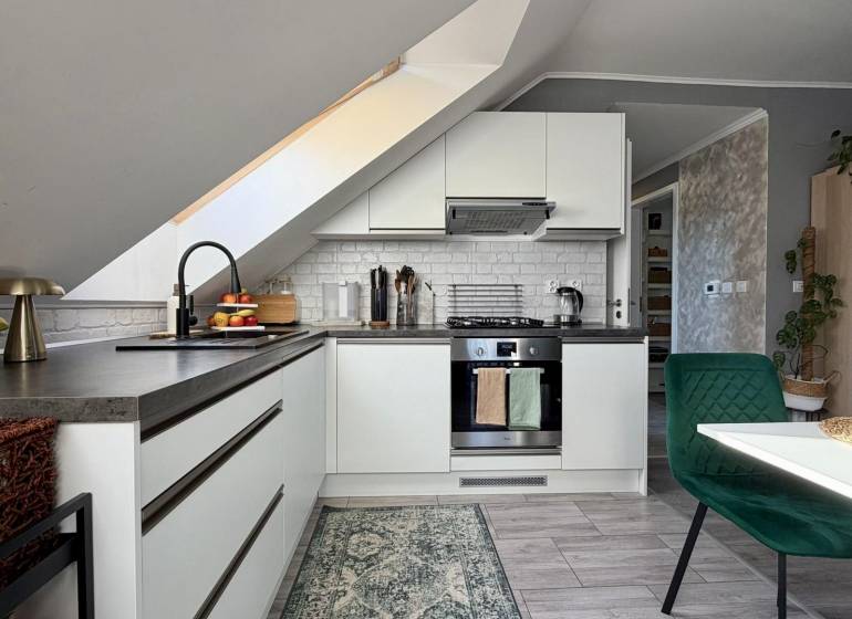 Küche in einer 2-Zimmer-Wohnung mit schräger Decke und Holzboden.