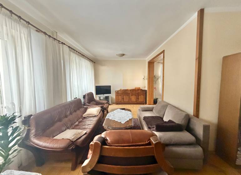 Wohnzimmer in einem Einfamilienhaus mit Holzboden, Sofa und Vorhängen.