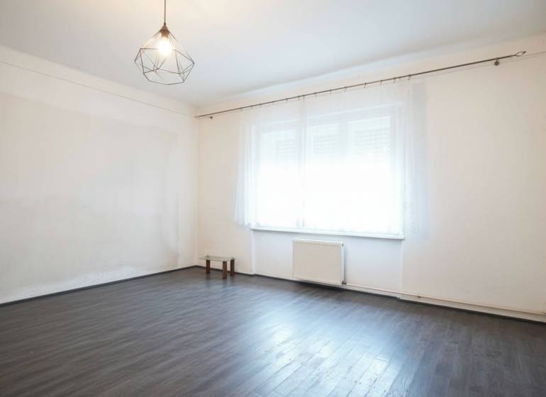 Ein Zimmer in einem Einfamilienhaus mit einem Boden in Holzoptik und einem großen Fenster.