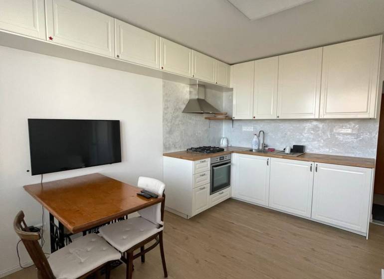 Küche in einer Einzimmerwohnung mit Holzboden und Esstisch.