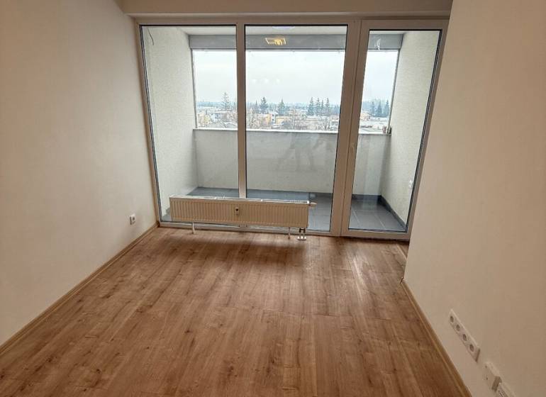 Wohnzimmer in einer Einzimmerwohnung mit Holzboden und großen Fenstern.