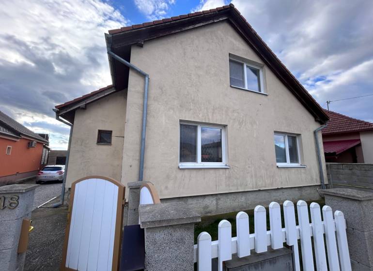 Ein Einfamilienhaus in Zbehy mit einem Schrägdach, einem Zaun und einer Zufahrtsstraße.