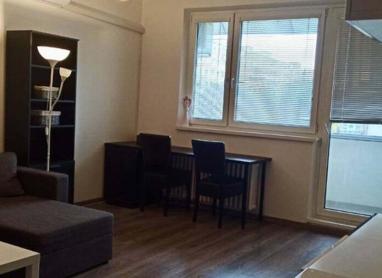 Wohnzimmer in einer Zweizimmerwohnung mit Ecksofa und Holzboden.