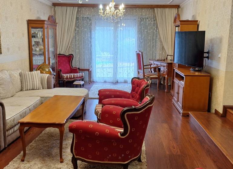 Wohnzimmer in einem Einfamilienhaus mit roten Sesseln und einem Boden in Holzoptik.