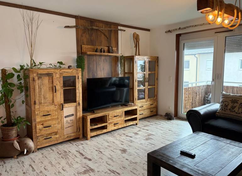 Wohnzimmer in einer 3-Zimmer-Wohnung mit Holzmöbeln und Boden in Holzoptik.