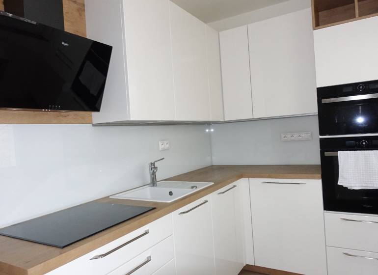 Eine Küche mit weißen Schränken und Geräten, ergänzt durch einen Bodenbelag in Holzoptik in einer 3-Zimmer-Wohnung.