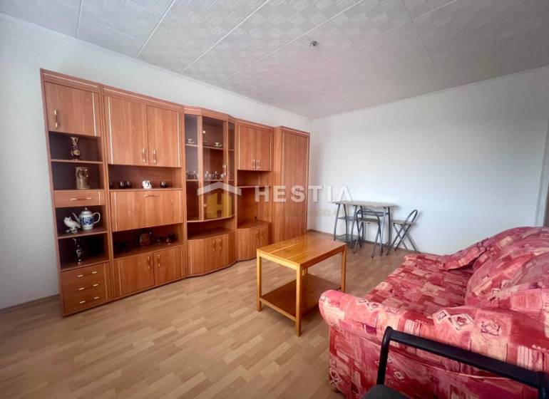 Wohnzimmer in einer 3-Zimmer-Wohnung mit rotem Sofa und Wohnwand aus Holz.