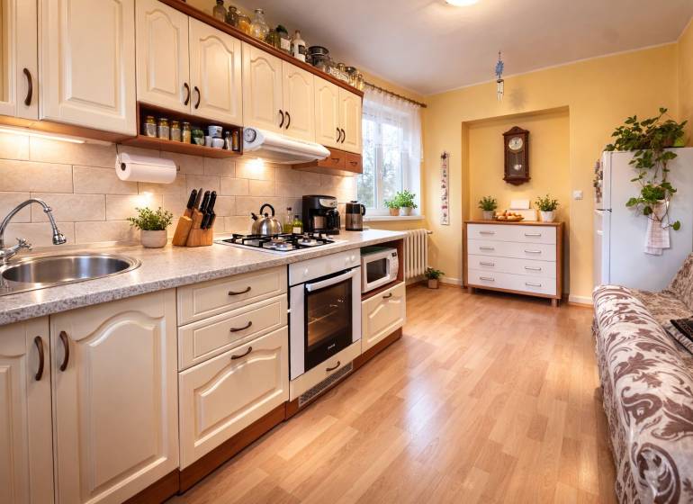 Küche in einer 2-Zimmer-Wohnung mit Holzboden, heller Küchenzeile und Pflanzen.