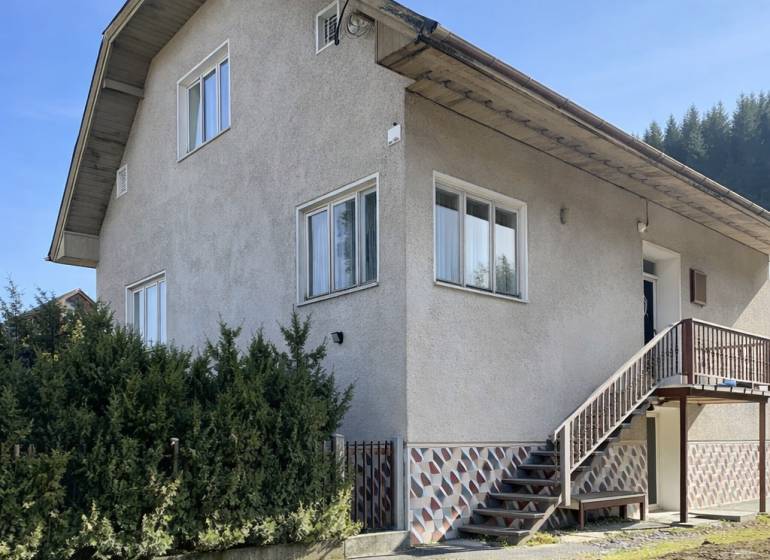 Ein Einfamilienhaus in Terchová mit großen Fenstern, einer Treppe und einem gepflegten Vorgarten.