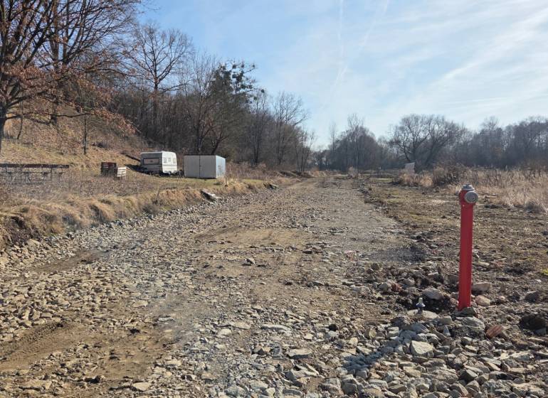 Grundstücke - Wohnen in Haniska, steiniger Weg zwischen Bäumen und Container.