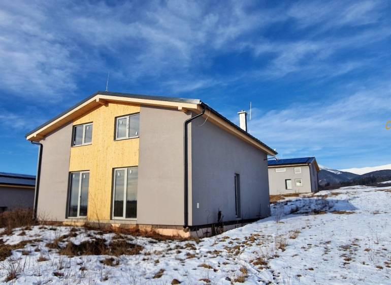 Eine Hütte in Dolná Lehota mit Holzverkleidung, verschneite Landschaft und Berge am Horizont.