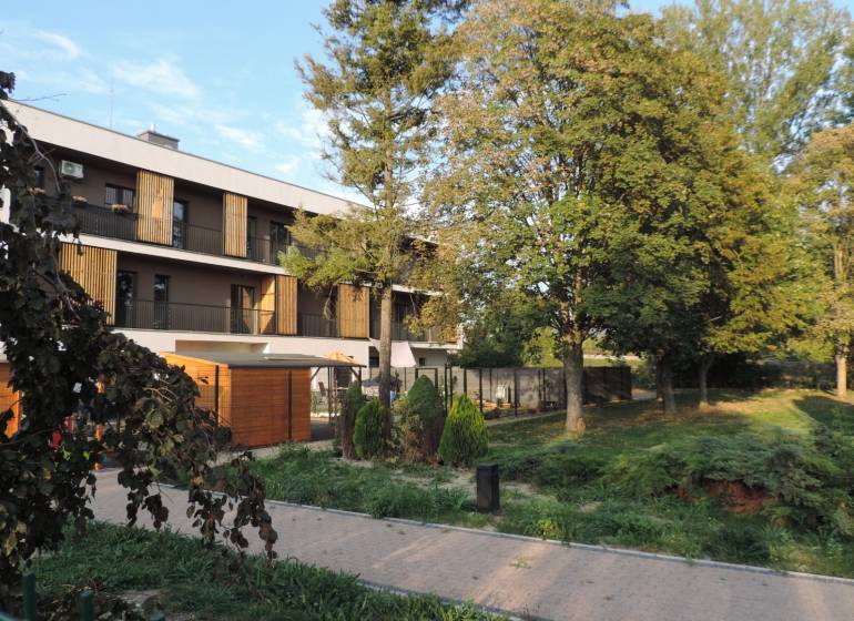 Das Wohnhaus in der Bodona-Straße, umgeben von Grünflächen und Bäumen, ideal für das Wohnen in einer Einzimmerwohnung.