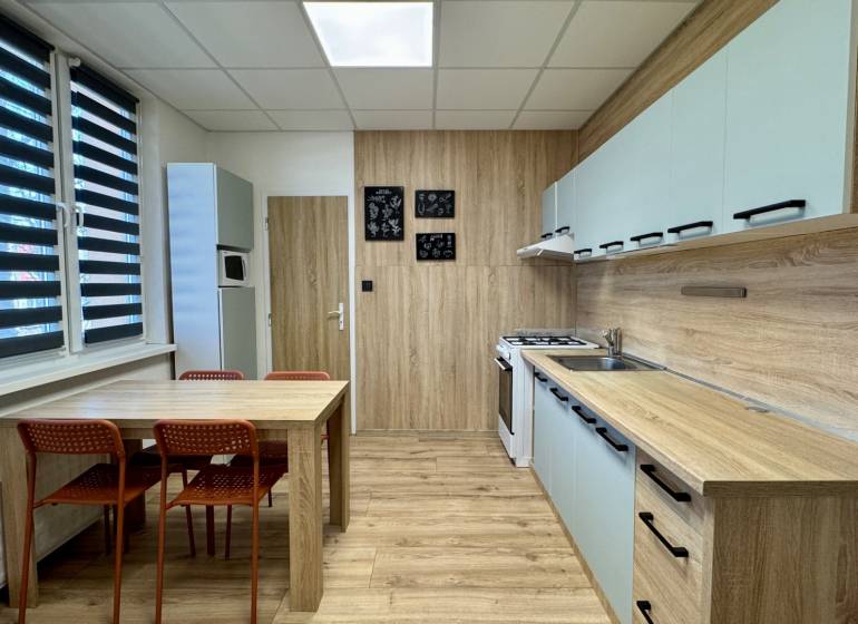 Küche in einer 3-Zimmer-Wohnung mit Esstisch und Boden mit Holzdekor.