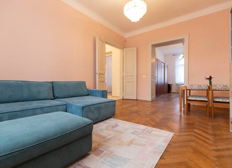 Ein Zimmer in einer 3-Zimmer-Wohnung mit einem blauen Sofa, einem Holzboden-Dekor und einem Essbereich.