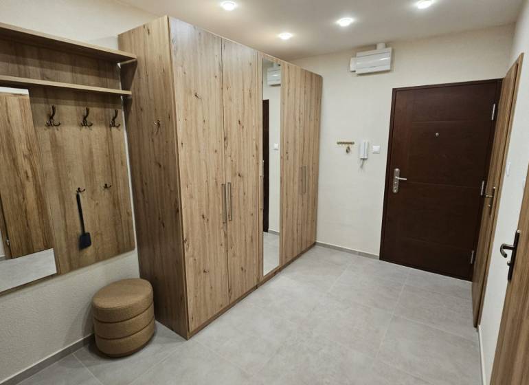 Der Flur in der 2-Zimmer-Wohnung mit Möbeln in Holzoptik und einem eingebauten Spiegel.