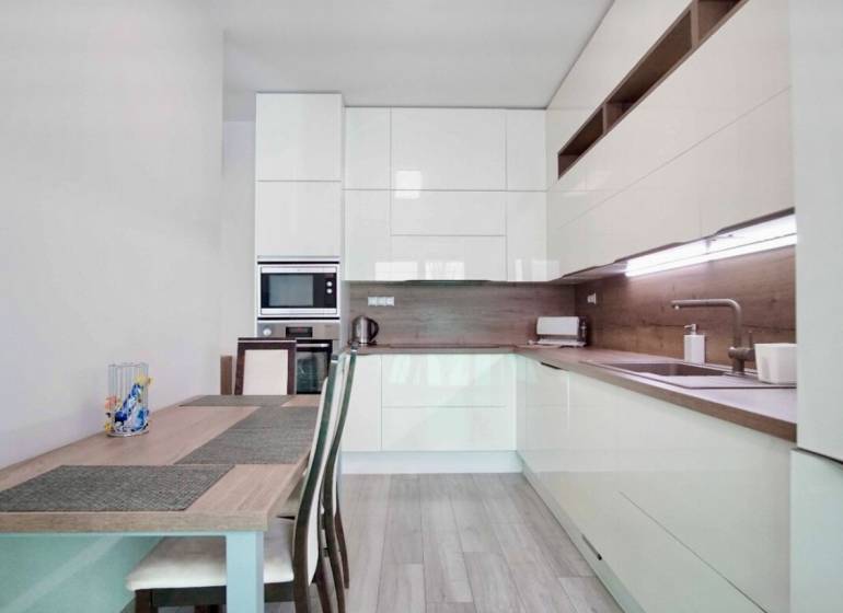 Küche in einer 3-Zimmer-Wohnung mit Holzboden und hellen Möbeln.