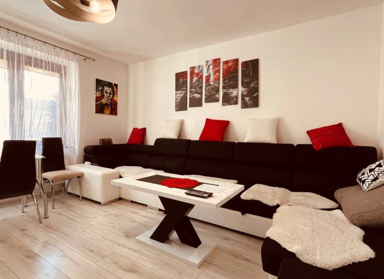 Wohnzimmer in einer 3-Zimmer-Wohnung, mit einem Sofa und einem Boden in Holzoptik.