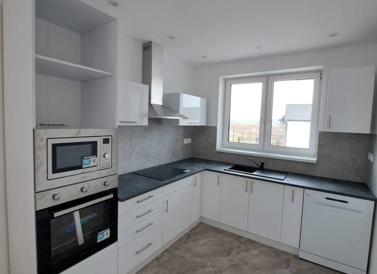 Küche in einem Einfamilienhaus mit weißen Schränken und eingebauten Geräten.