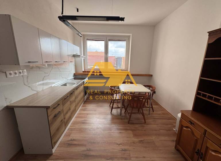 Küche in einer Einzimmerwohnung mit Tisch, Stühlen und Boden in Holzoptik.