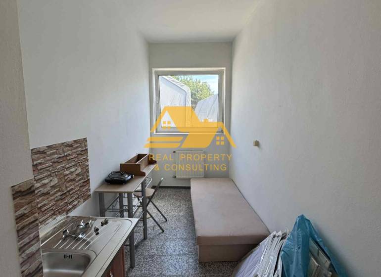 Kleine Garçonnière mit Waschbecken, Tisch und Liege, geeignet für praktisches Wohnen.