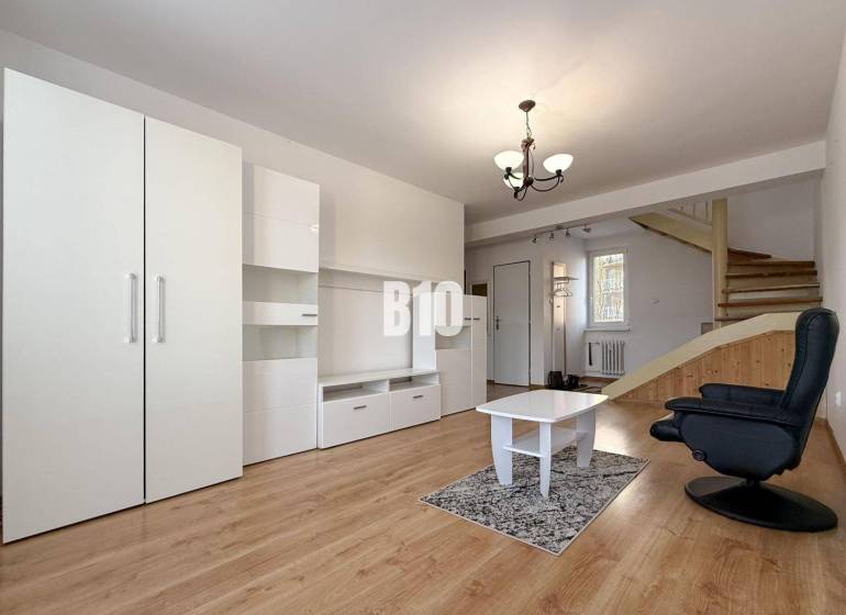 Wohnzimmer in einer Ferienwohnung mit weißen Möbeln und einem Boden in Holzoptik.