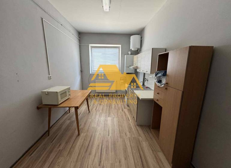 Einfache Einrichtung eines Einzimmerapartments mit Küchenzeile und Holzboden.