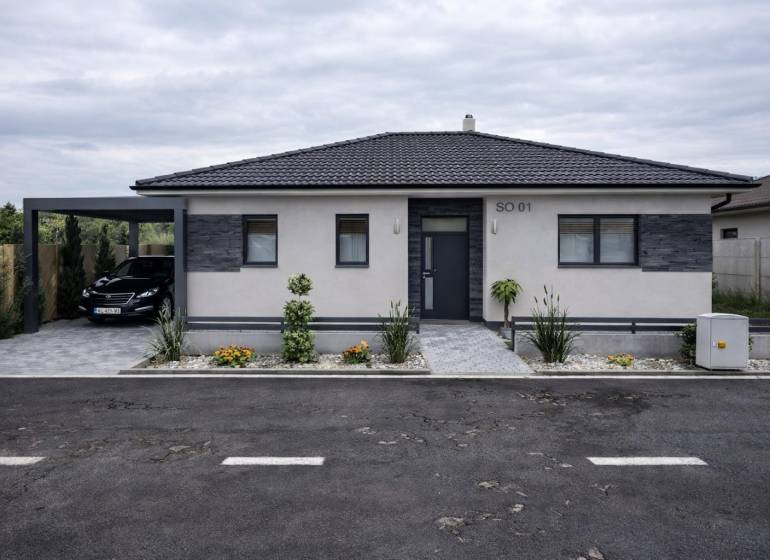 Ein Einfamilienhaus in Urmince mit eleganter Fassade und einem Parkplatz.