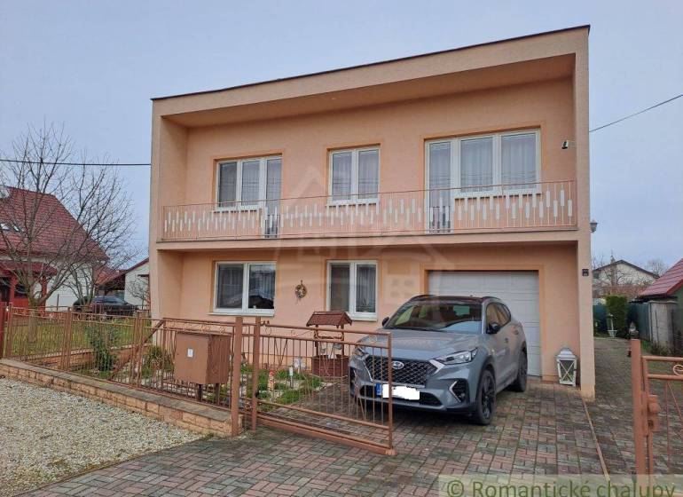 Ein Einfamilienhaus in Veľké Ripňany mit einem Balkon und einem Auto in der Einfahrt.