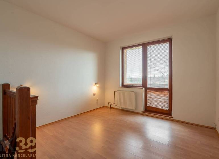 Ein Zimmer mit einem Boden in Holzoptik in einer Wohnung mit fünf oder mehr Zimmern, helle Wände, großes Fenster.