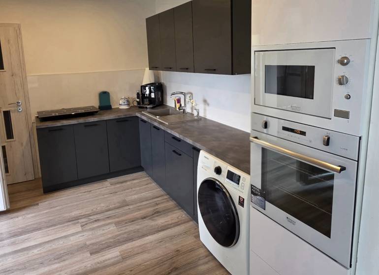 Küche in einer 3-Zimmer-Wohnung mit schwarzen Schränken und einem Boden in Holzoptik.