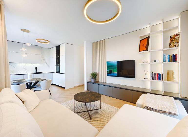 Wohnzimmer einer Zweizimmerwohnung mit Sofa, Küche und Holzboden.