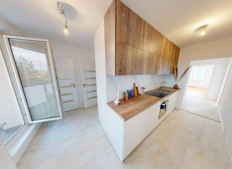 Küche in einer 2-Zimmer-Wohnung mit hellem Boden und Schränken in Holzoptik.