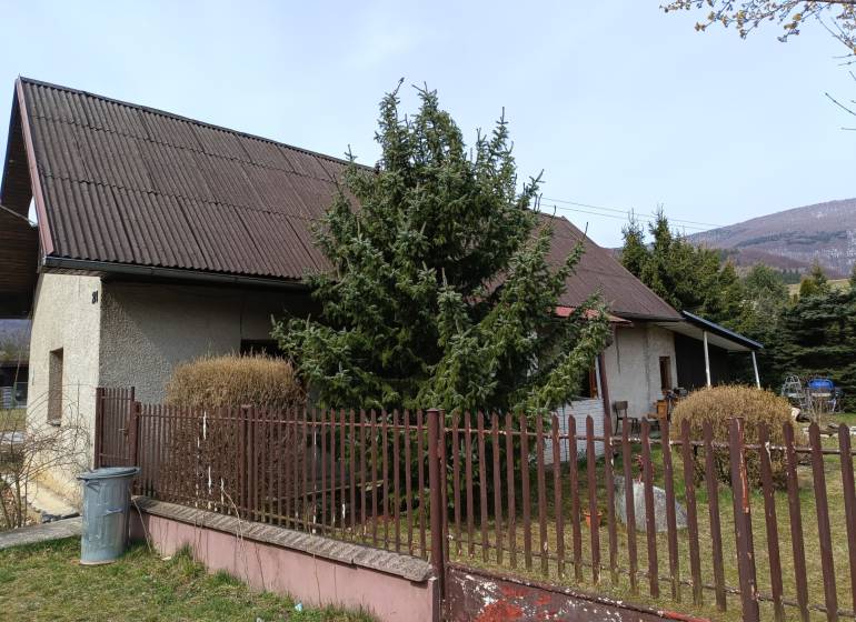 Ein Einfamilienhaus in Vrícko mit einem eingezäunten Garten bei einem Nadelbaum.