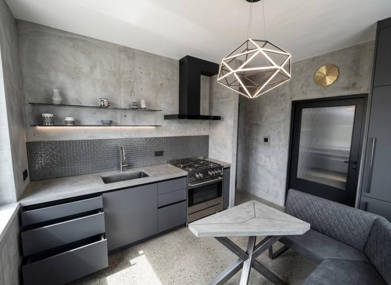 Küche in einer 2-Zimmer-Wohnung mit Betonoptik und geometrischer Leuchte.