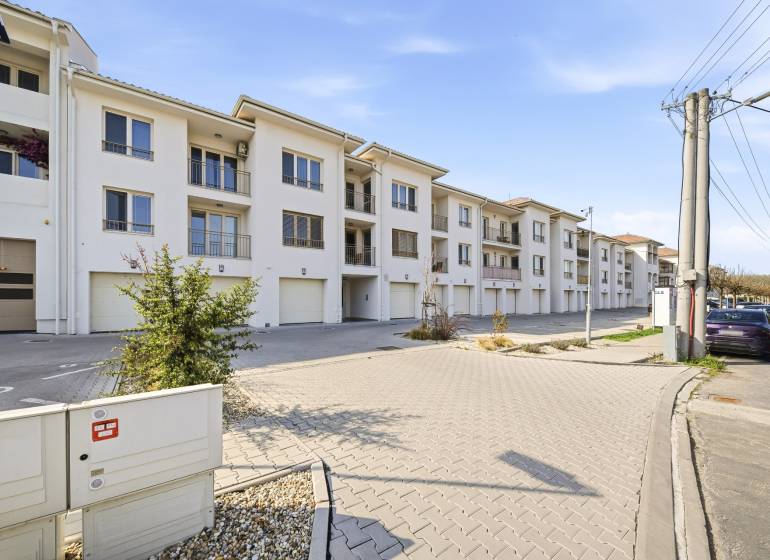 Außenbereich einer 4-Zimmer-Wohnung in Dunajská Streda mit heller Fassade und Garagen.