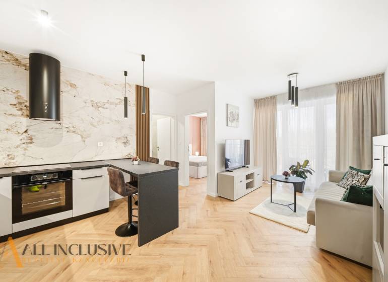 Wohnzimmer und Küche in einer 4-Zimmer-Wohnung mit Holzboden und heller Dekoration.
