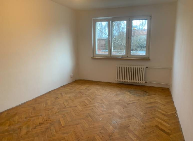 Ein Zimmer in einer 2-Zimmer-Wohnung mit einem Boden in Holzoptik und einem großen Fenster.