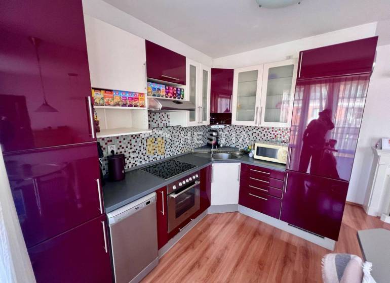 Küche in einer Einzimmerwohnung mit glänzenden Schränken und Mosaik an der Wand.