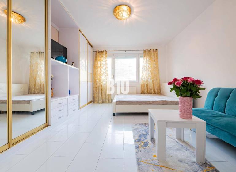 Wohnzimmer in einer Einzimmerwohnung mit einem Spiegelschrank und weißen Böden.