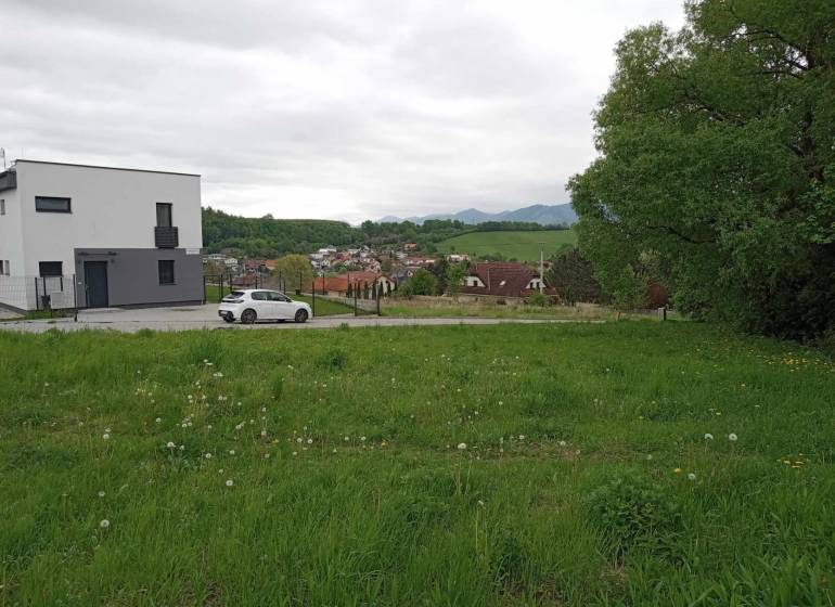 Grundstücke - Wohnen in Žilina auf der Chotárna zeigen eine grüne Wiese mit einem modernen Gebäude und einem Auto.