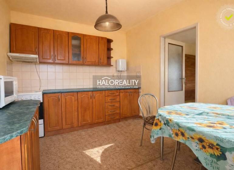 Küche in einem Einfamilienhaus mit Einbauschränken und einem Tisch mit geblümter Tischdecke.