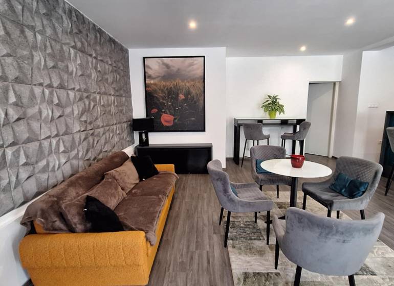 Wohnzimmer in einem Einfamilienhaus mit bequemen Sofa und Essstühlen.