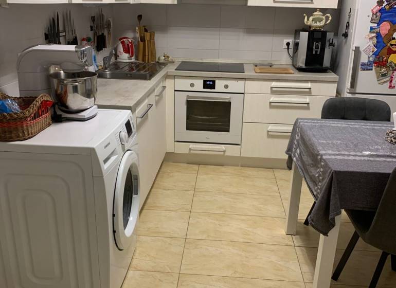 Küche in einer 2-Zimmer-Wohnung mit weißen Schränken und Keramikboden.